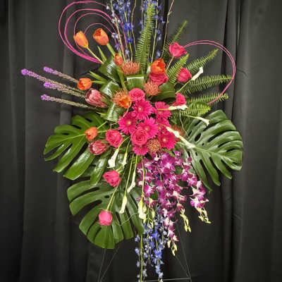 Tall tropical floral spray with pink and orange blooms on a stand