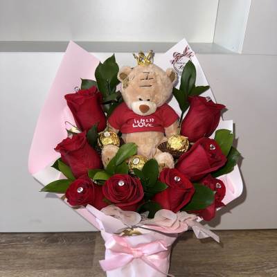 Bouquet of red roses with a teddy bear and chocolates in pink wrapping