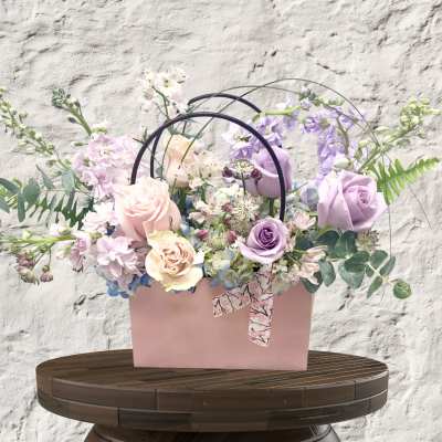 Pastel flower arrangement in a pink box with arched handles
