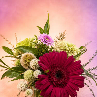 Gerbera daisy arrangement in a square glass vase with mixed blooms