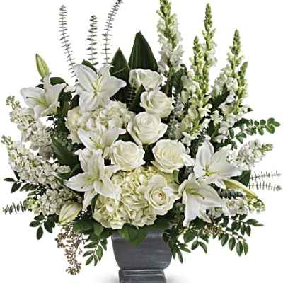 Large all-white arrangement of lilies, roses, hydrangeas and snapdragons in a gray urn vase