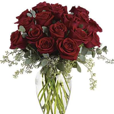 Arrangement of long-stem red roses with filler in a clear glass vase