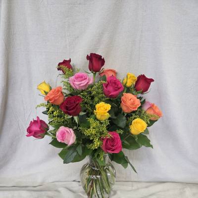 Mixed bouquet of colorful roses arranged in a clear glass vase.