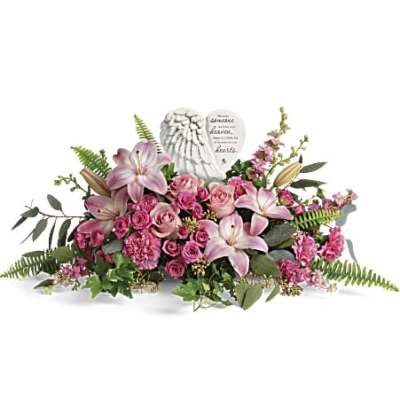 Pink lily and rose sympathy arrangement with angel-wing memorial stone in a low horizontal design.