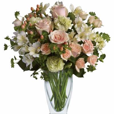 Vase arrangement of peach roses, green carnations, and white alstroemeria in a clear glass vase