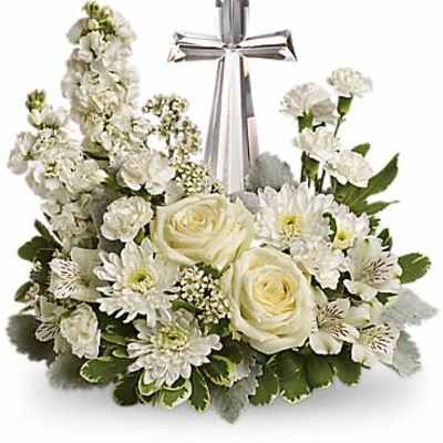 Low white floral arrangement with roses, mums, and a glass cross in the center