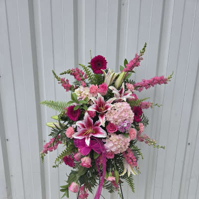 Standing spray of pink lilies, roses, carnations, gerbera daisies, and hydrangeas on a metal easel