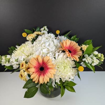Peach gerbera daisies and white chrysanthemums in a glass vase