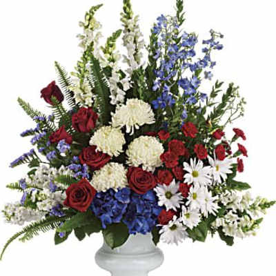 Tall red, white, and blue flower arrangement in a white urn-style vase
