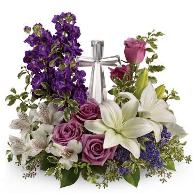 Sympathy arrangement with white lilies, purple roses, and a glass cross centerpiece