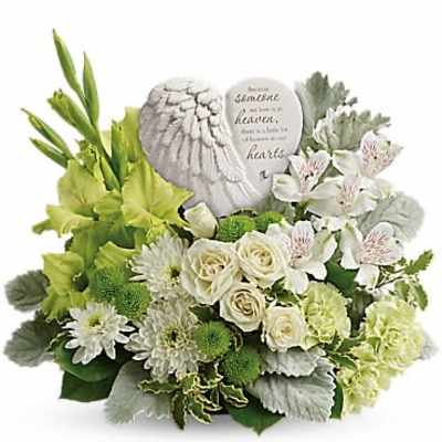 Low green and white sympathy arrangement with roses, mums, alstroemeria and an angel-wing heart plaque.