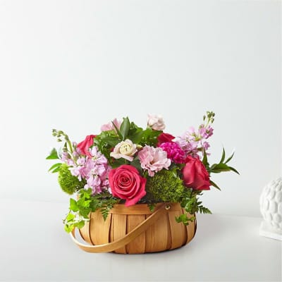 Pink and red roses arranged in a woven basket