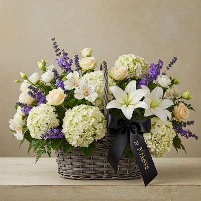 Basket arrangement of white lilies, cream roses, and purple flowers