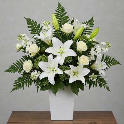 White lilies and roses arranged in a white vase