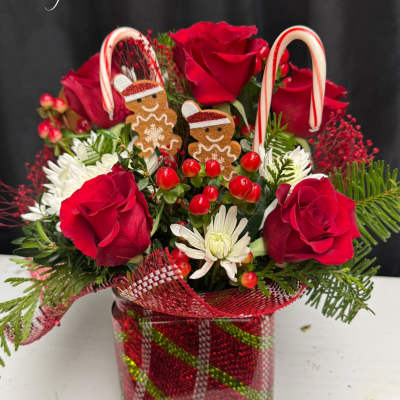 Red roses and white daisies in a glass vase with candy cane decorations
