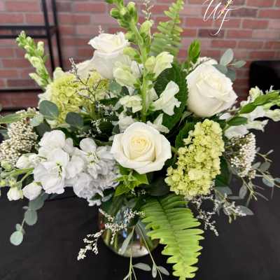 White roses and pale green hydrangeas in a glass vase