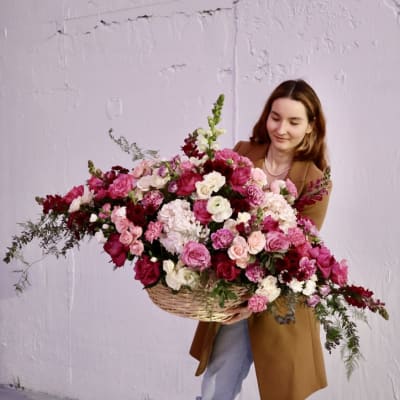 Woman holding a large basket of pink and white flowers
