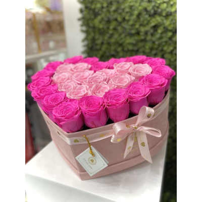 Heart-shaped pink hat box filled with hot pink and light pink roses with a ribbon bow.