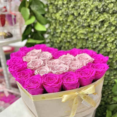 Heart-shaped box of hot pink and pale pink roses tied with a satin ribbon
