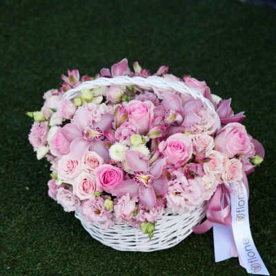 Pink roses and orchids arranged in a white basket with ribbon