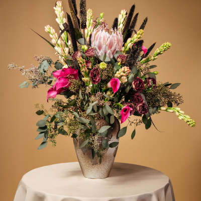 Tall floral arrangement in a textured vase with pink and white blooms