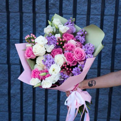 Bouquet of pink, white, and purple roses wrapped in pastel paper