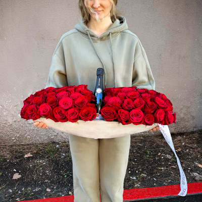 Woman holding a large tray of red roses with a champagne bottle in the center