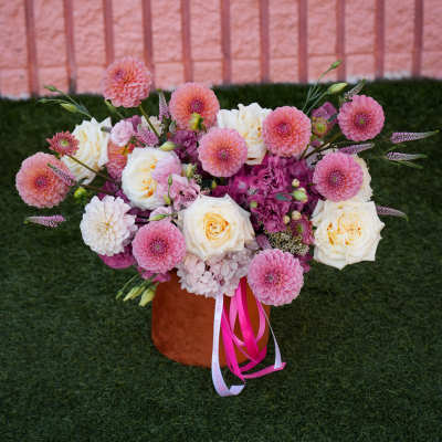 Pink and white floral arrangement in a brown vase with ribbon