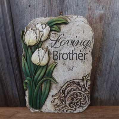 Stone memorial plaque with white tulips and the inscription Loving Brother.