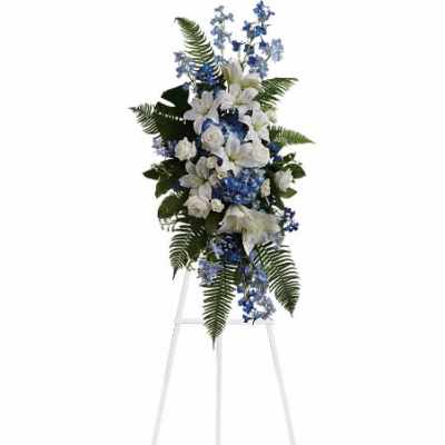 Tall white and blue standing spray with lilies and roses on a white easel