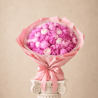 Pink bouquet of tightly packed blooms wrapped in satin ribbon