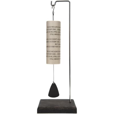 Memorial wind chime with printed remembrance text on a stand with wooden base