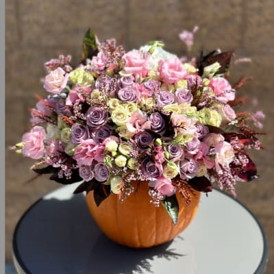 Pink and lavender rose arrangement in a pumpkin container