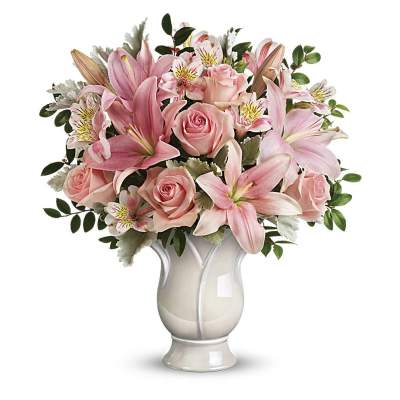 Arrangement of pink lilies, roses, and alstroemeria in a white ceramic vase