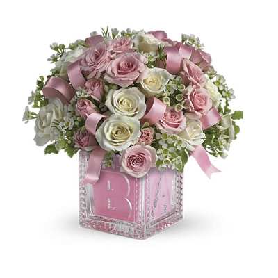 Compact pink and white rose arrangement with pink ribbons in a pink baby-block cube vase