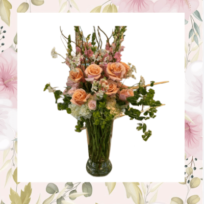Peach roses and pink flowers arranged in a glass vase