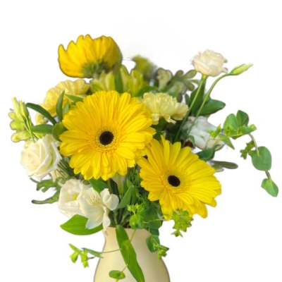 Yellow gerbera daisies and white flowers in a cream vase