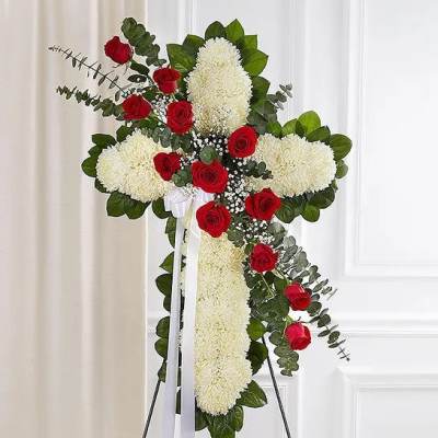 Standing floral cross of white mums accented with red roses and white filler flowers