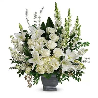 Tall white arrangement of lilies, roses, hydrangeas, and snapdragons in a gray pedestal vase