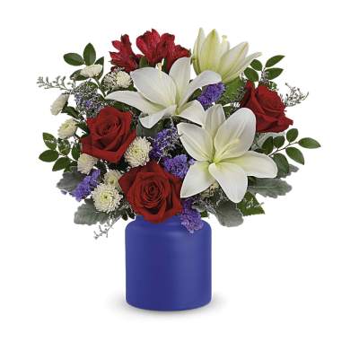 Arrangement of red roses, white lilies, and purple flowers in a matte blue vase