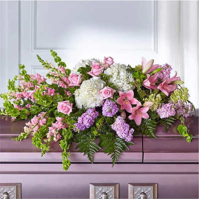 Pastel pink and white casket spray with roses, lilies, hydrangeas and lavender flowers on a mauve casket