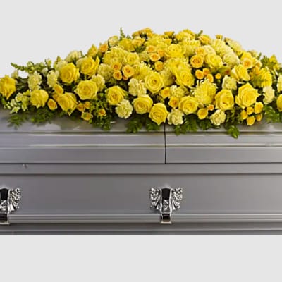 Yellow and cream casket spray of roses and other flowers on a silver casket