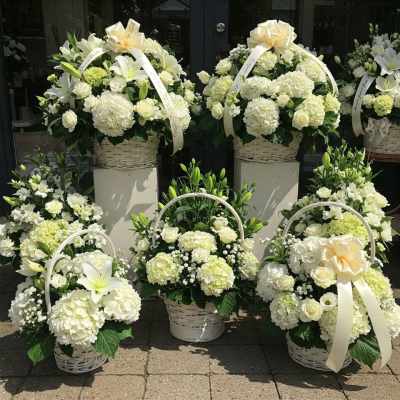 White floral basket arrangements with ribbons and lilies