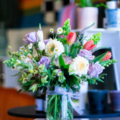 Mixed bouquet of pastel flowers in a glass vase with a ribbon