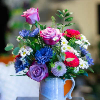 Mixed bouquet of roses and daisies in a blue ceramic mug