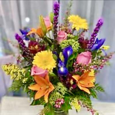 Colorful mixed bouquet with lilies, roses, and daisies in a vase