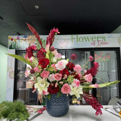 Large pink and red floral arrangement in a blue vase