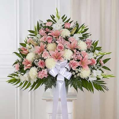 Large pink and white floral arrangement with a white bow displayed on a pedestal