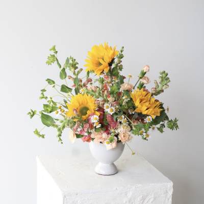 Mixed bouquet with sunflowers and small daisies in a white vase