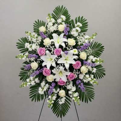 Standing floral spray with white lilies, roses, and purple accents